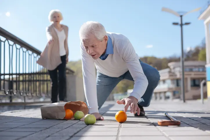 Stephen C. Carter, PC Attorney at Law | Hartwell, GA | old man falling down on street, dropping cane and groceries, with woman nearby helping