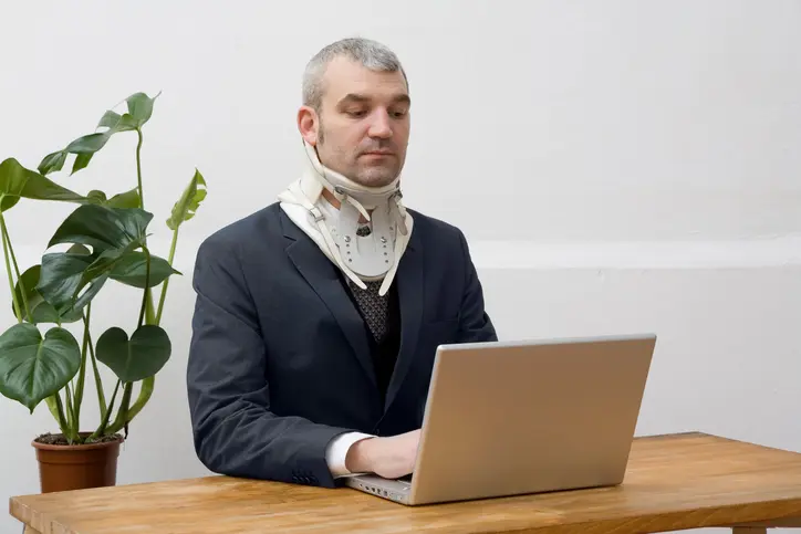 Stephen C. Carter, PC Attorney at Law | Hartwell, GA | a businessman wearing a neck brace working on his laptop